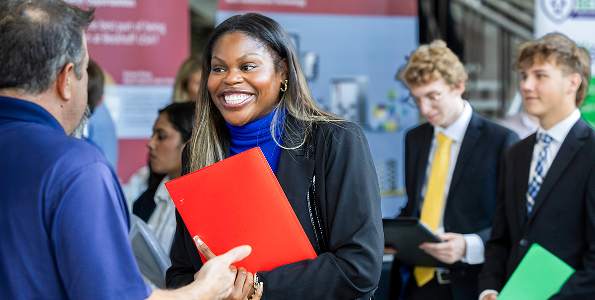 Candidate smiling talking to an employer at the Career Fair